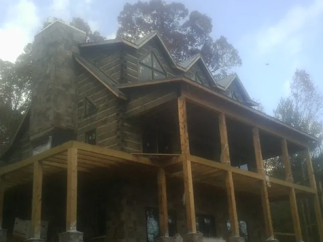 Stone chimney and dormers on a large log home with a timber porch in Port Hueneme