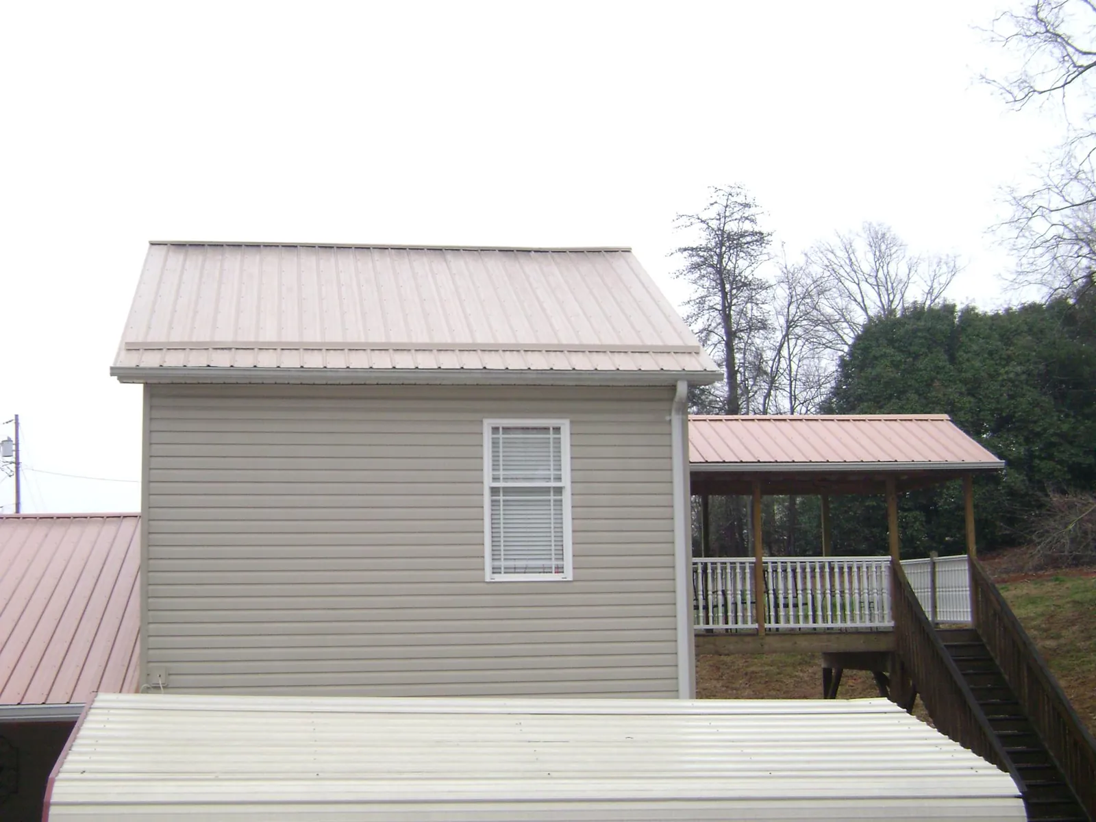Tan metal roofs on a two story addition and attached porch, from a Roof Replacement job in Port Hueneme